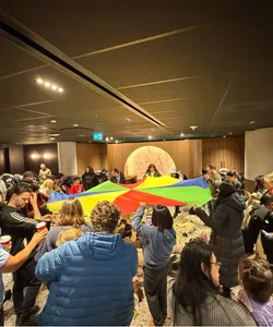 Karla playing with a parachute with a group of children and their families at a birthday circle time