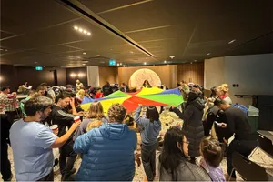 Karla playing with a parachute with a group of children and their families at a birthday circle time