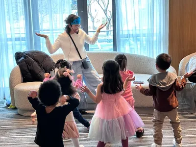 Karla, wearing a blue crown, dances and plays with children at a themed birthday party.