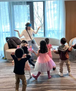 Karla, wearing a blue crown, dances and plays with children at a themed birthday party.